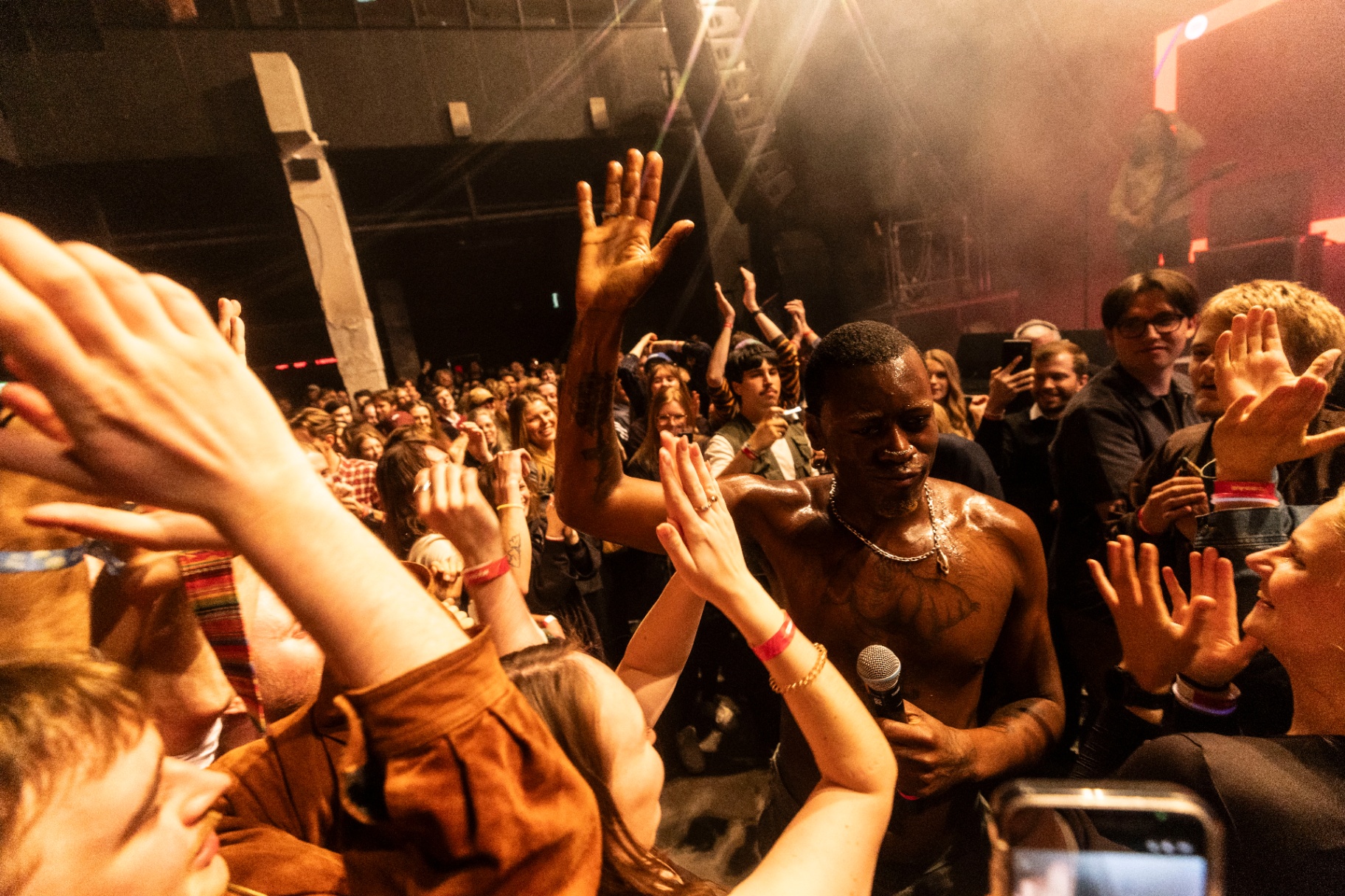 Boko Yout in the middle of the crowd at Fållan, microphone in hand, fans with arms raised dancing around him