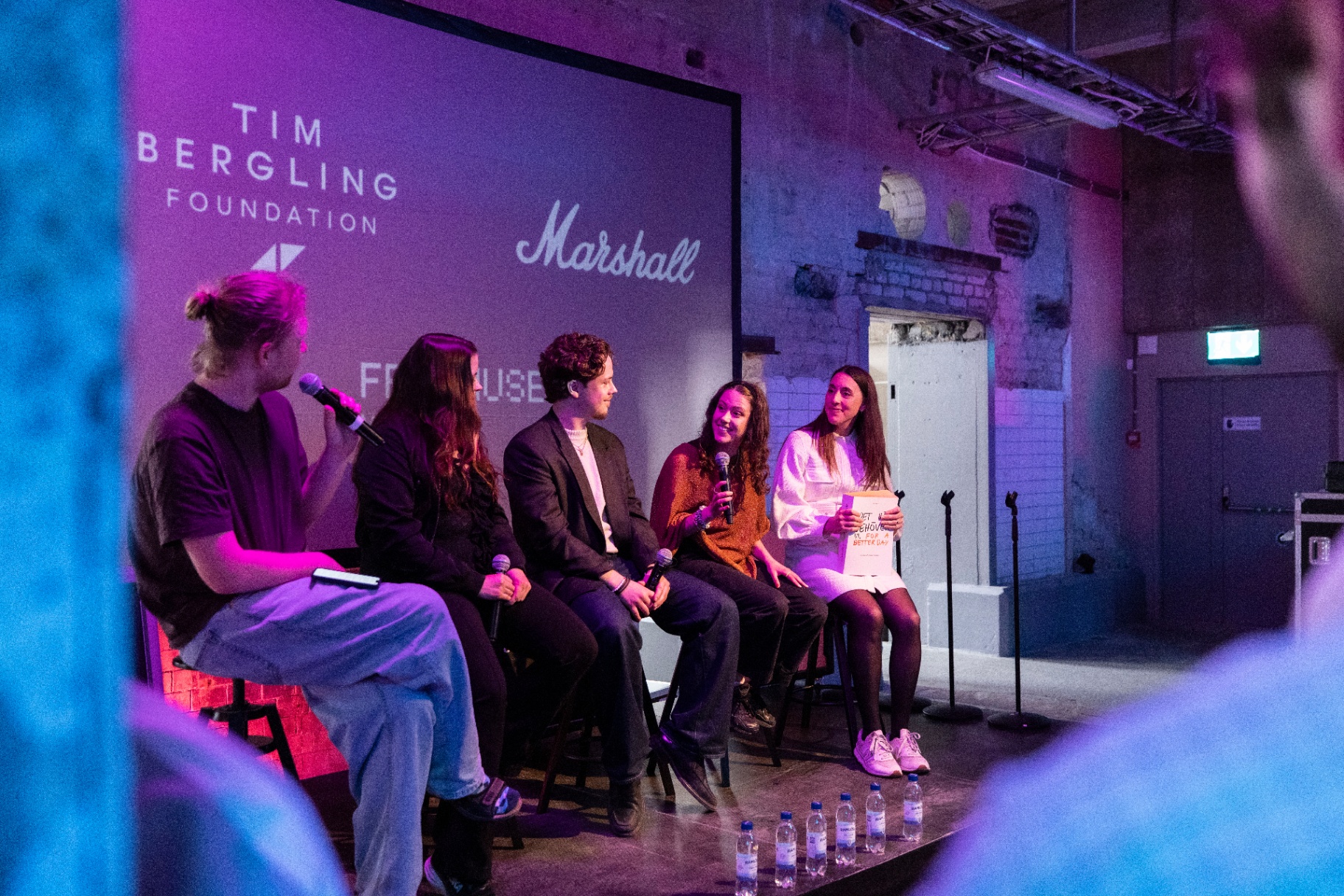 Panelists with microphones on stage in front of a backdrop showing the Tim Bergling Foundation, Marshall and Fryshuset logos.