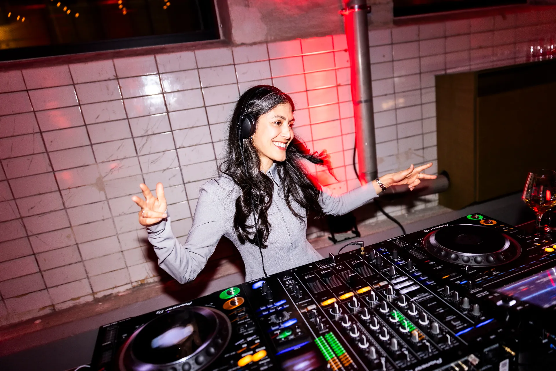 A DJ with headphones smiling behind a Pioneer mixer
