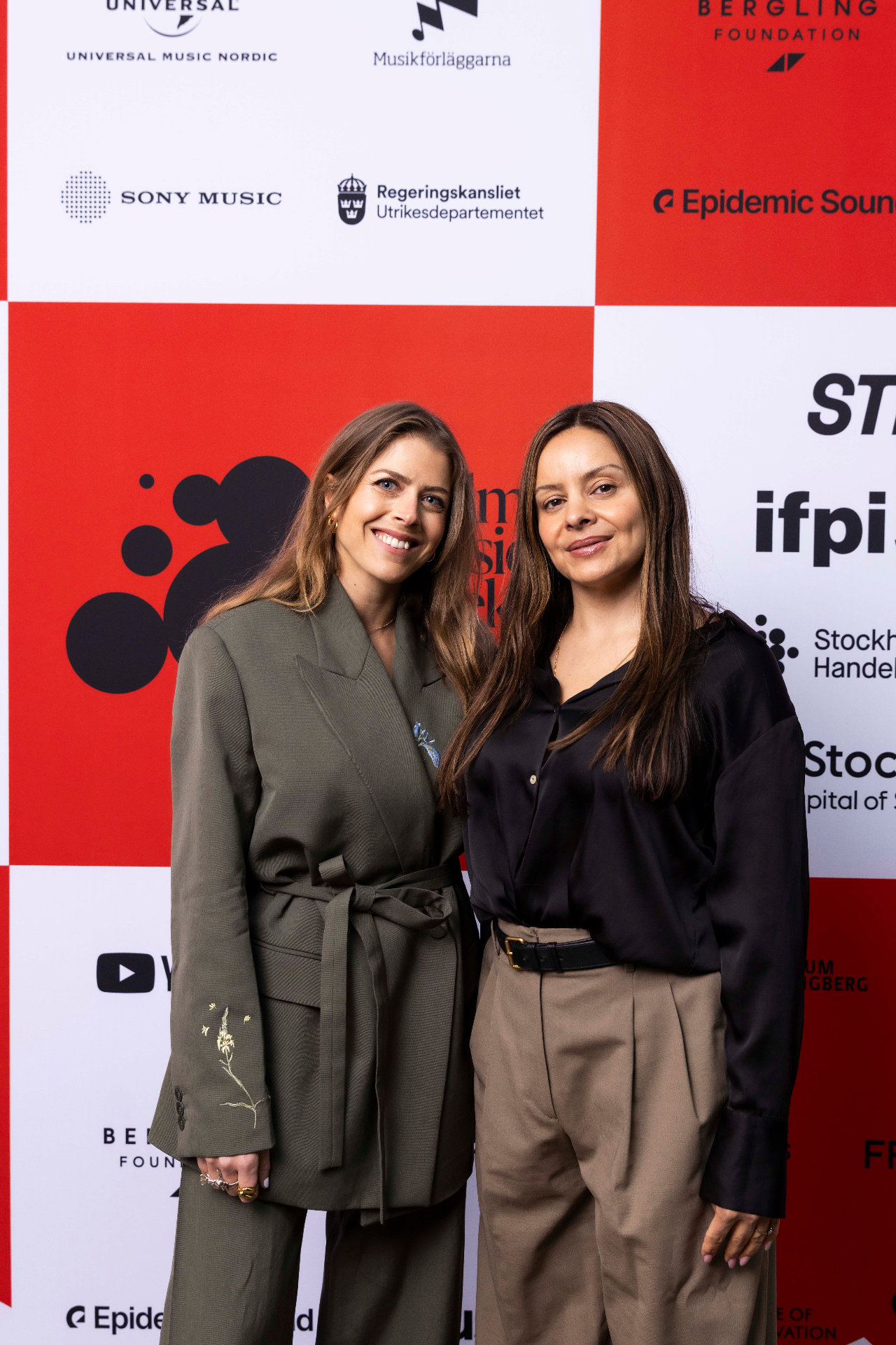 Andrea Lewis Åkerman and Michelle Kadir in front of the photo wall