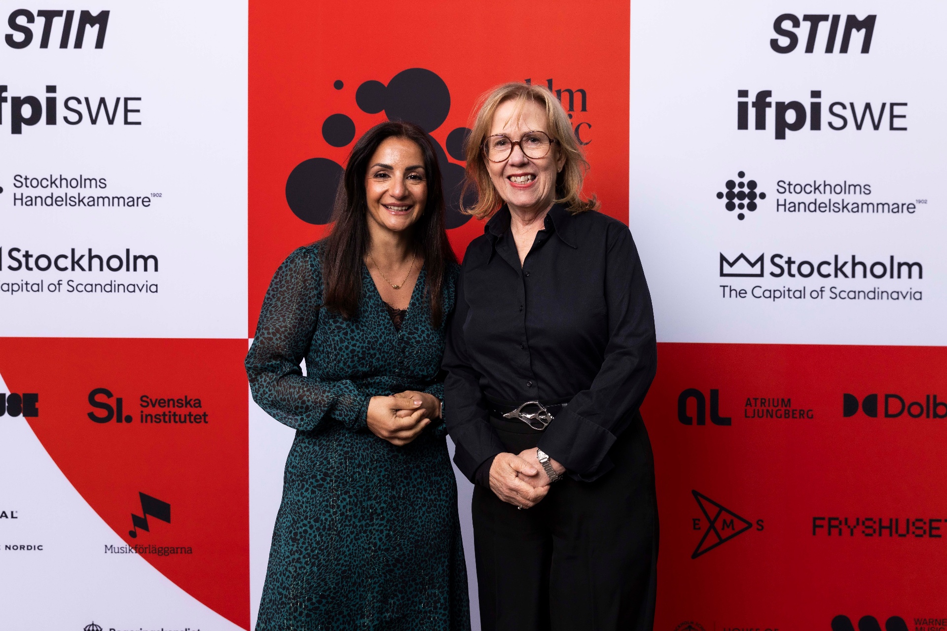 Parisa Liljestrand and Madeleine Sjöstedt in front of the photo wall